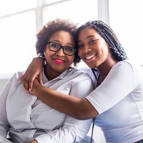 Mother and daughter sitting on sofa