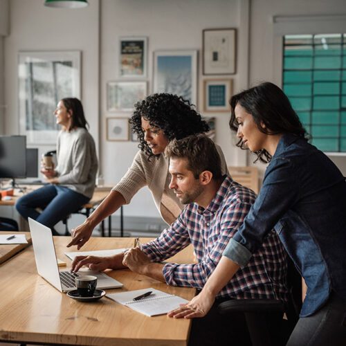 Three people using a laptop together at work